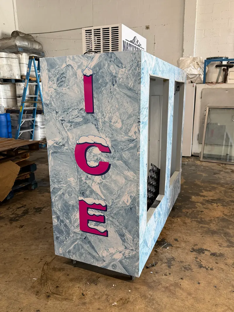 Side of an ice merchandiser with pink ICE lettering over an ice-cube wrap